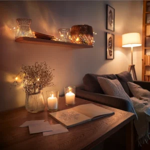 Salón acogedor con velas encendidas, luces tenues, sobres sobre una mesa y un cuaderno abierto con dibujos. Escena preparada para un escape room casero con atmósfera de misterio y calma.